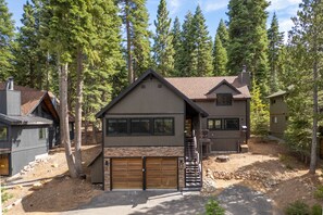 A two-story house with a stone facade, a wooden garage, and a staircase leading to the second floor.