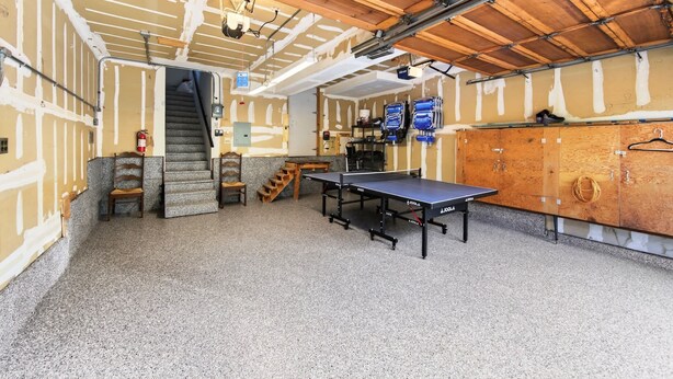 Una habitación con mesa de ping pong, armarios de madera y una escalera.