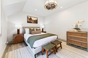 A bedroom with a bed, bedside tables, a dresser, a bench, a painting, and a ceiling fan. - The Seasons Tahoe 4bdr Cabin (Tahoe Vista)