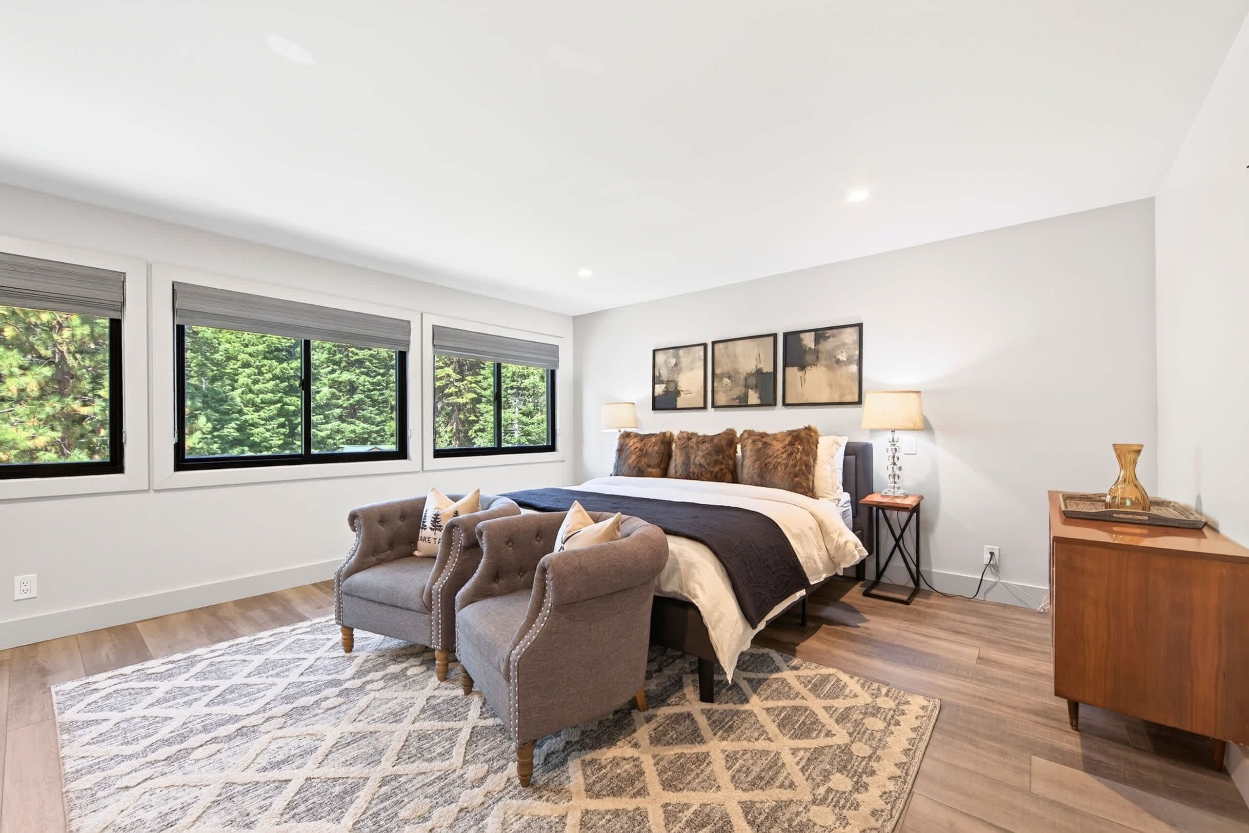 Une chambre à coucher avec un grand lit, deux fauteuils, une table de chevet et une commode.