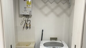 A laundry room with a washing machine, a sink, and a water heater.