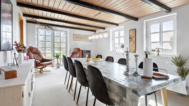 A spacious dining area with a long table, black chairs, and a modern chandelier.