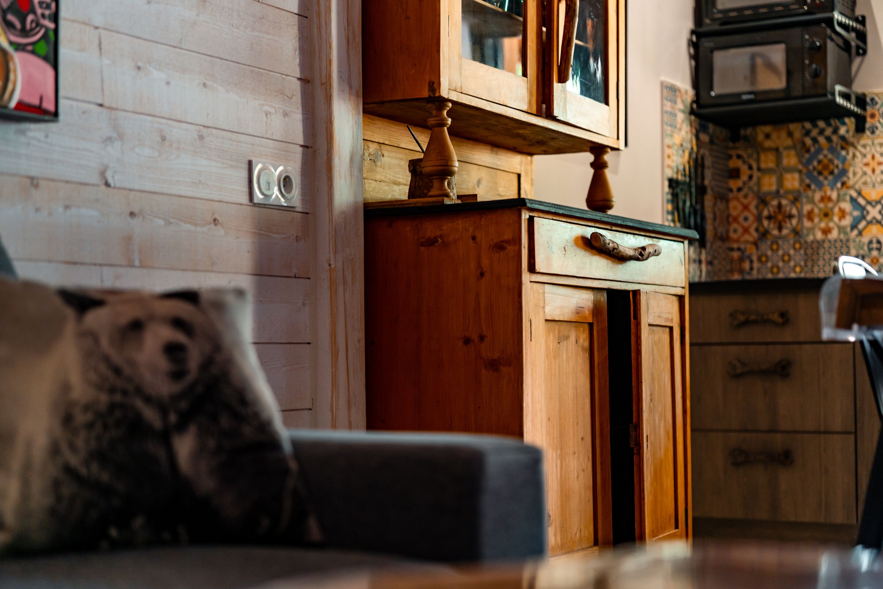 Un intérieur en bois comprenant un canapé, un meuble en bois et un mur recouvert de carreaux.