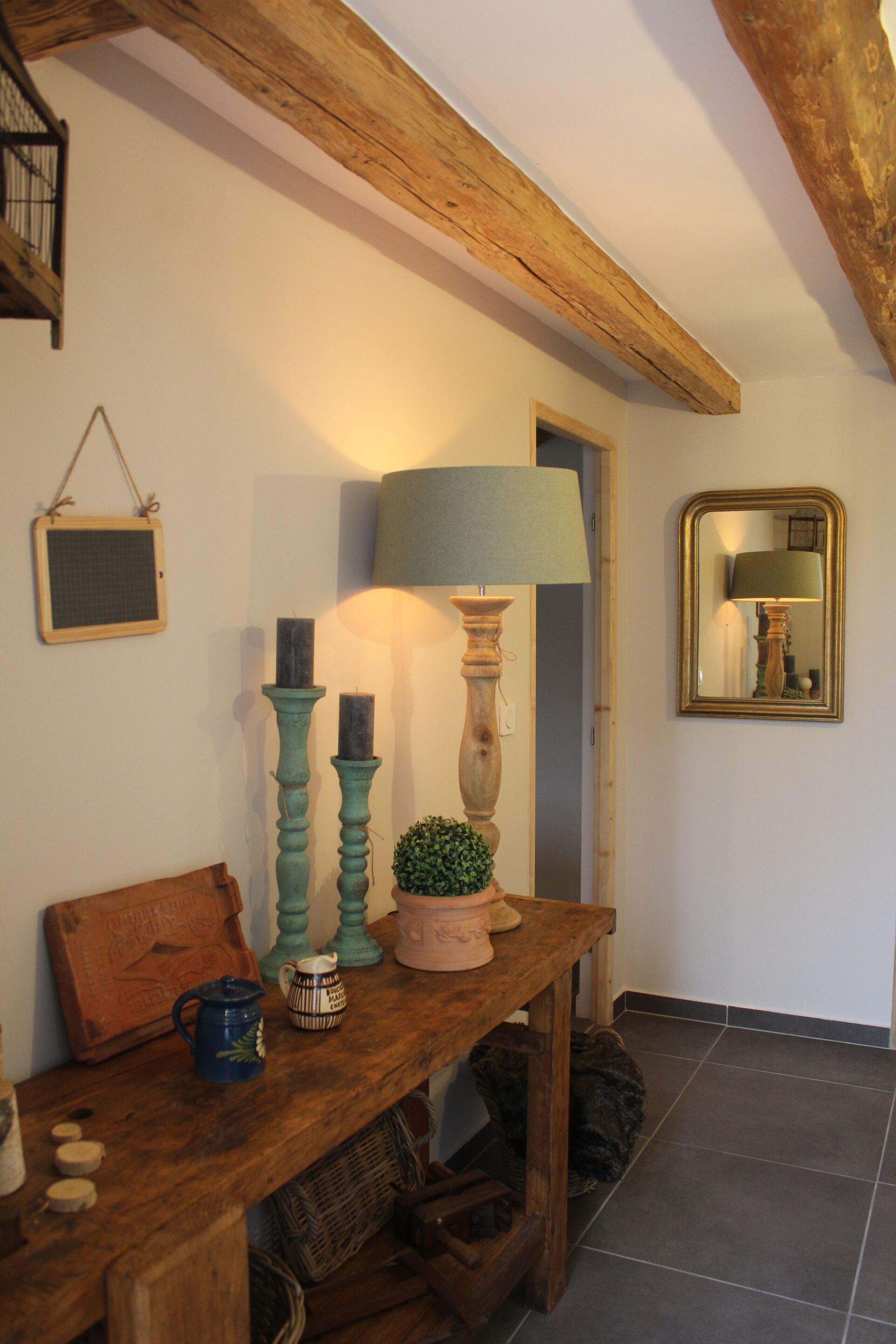 Ein Holzkonsolentisch mit Kerzen, einer Lampe und einem Spiegel.
