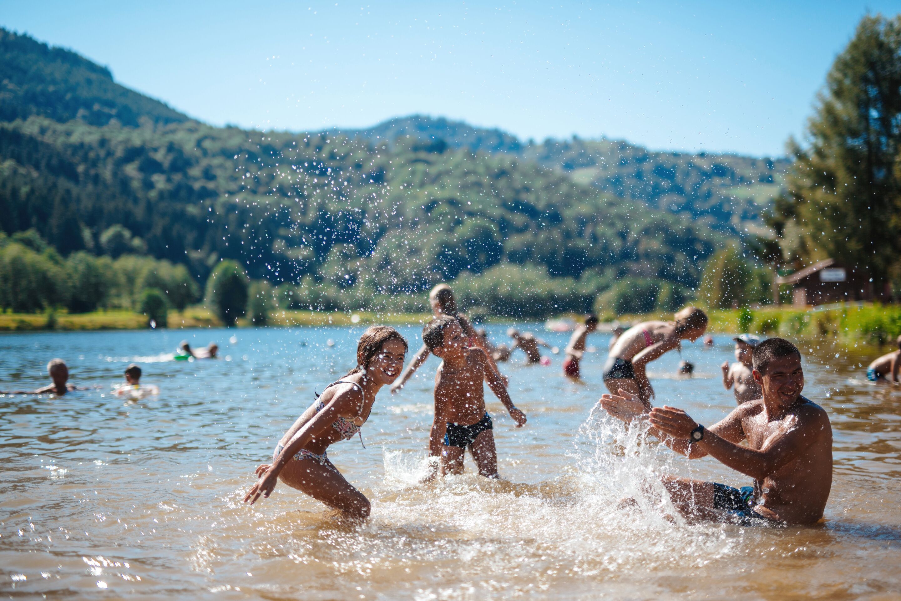 Eine Gruppe von Menschen schwimmt in einem See vor einer Bergkulisse.