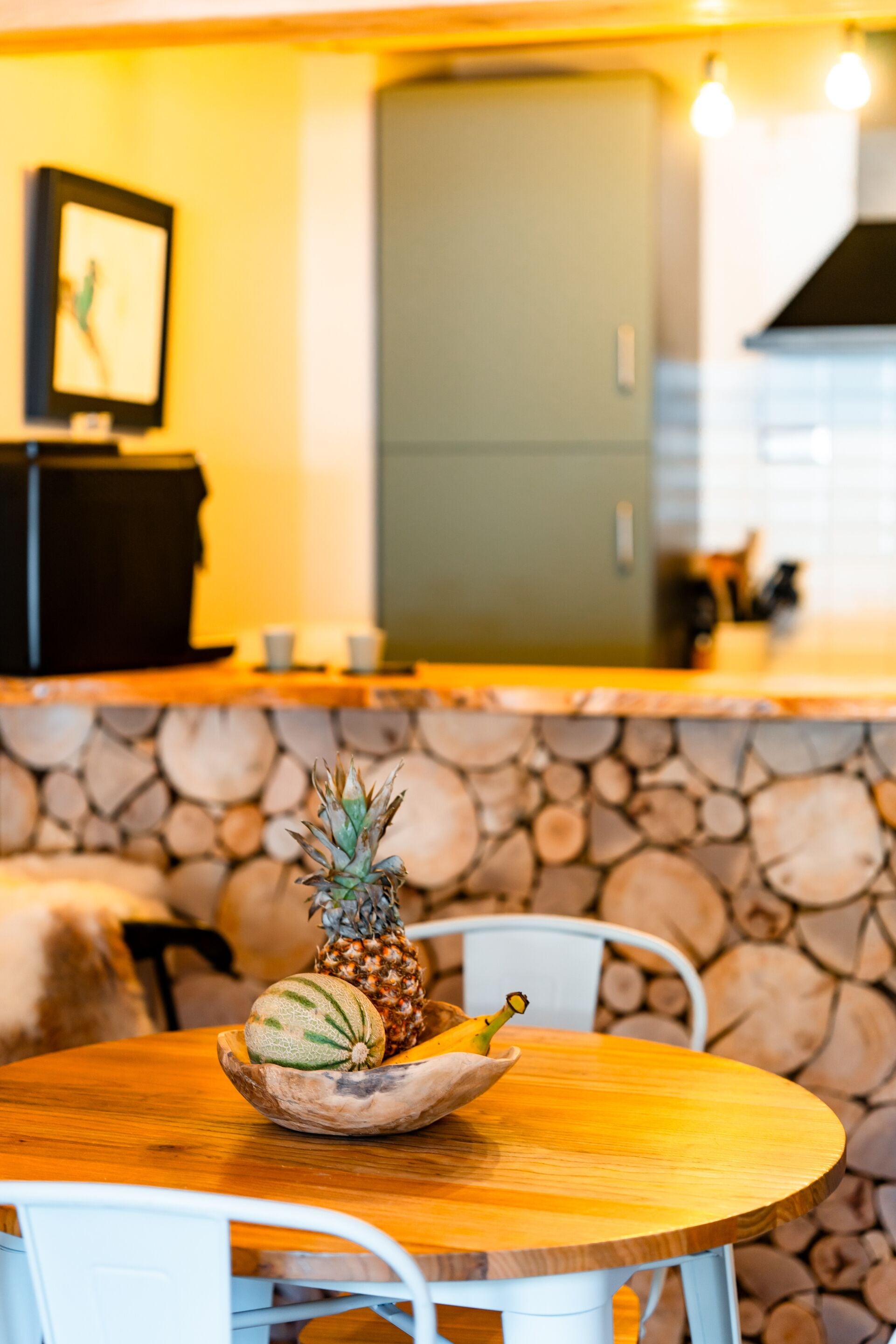 Ein Holztisch mit einer Schüssel, die eine Ananas und eine Melone enthält.