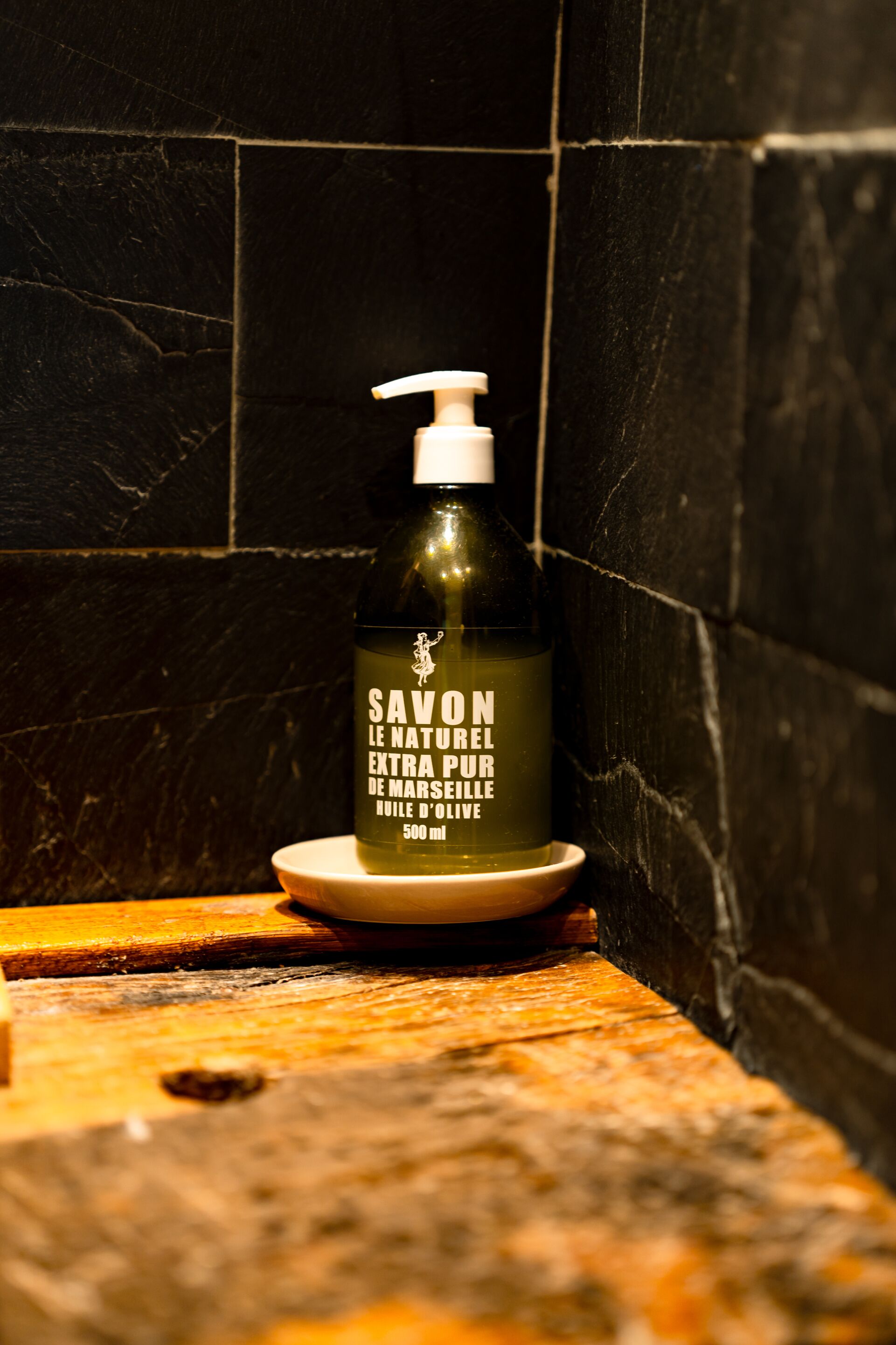 Una botella de Savon Le Naturel Extra Pur De Marseille sobre una superficie de madera.