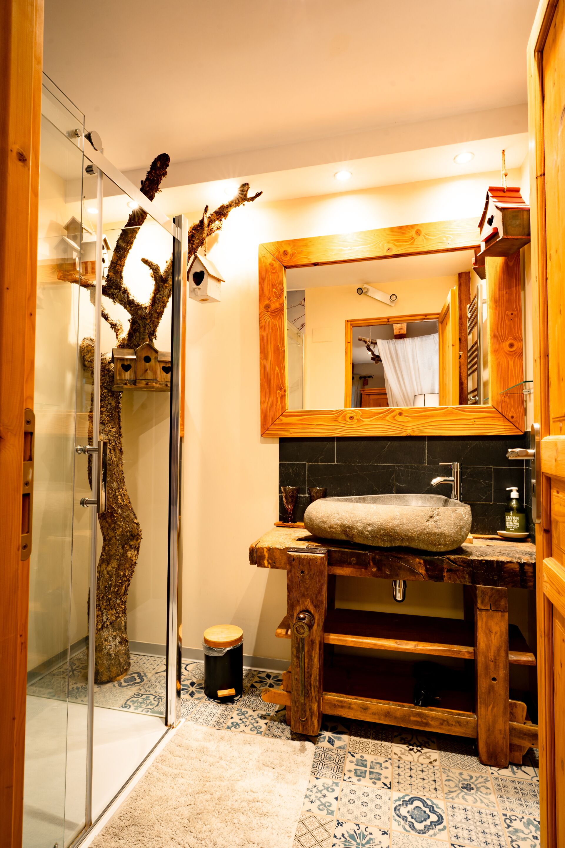 A bathroom with a stone sink, wooden vanity, and a glass shower enclosure.
