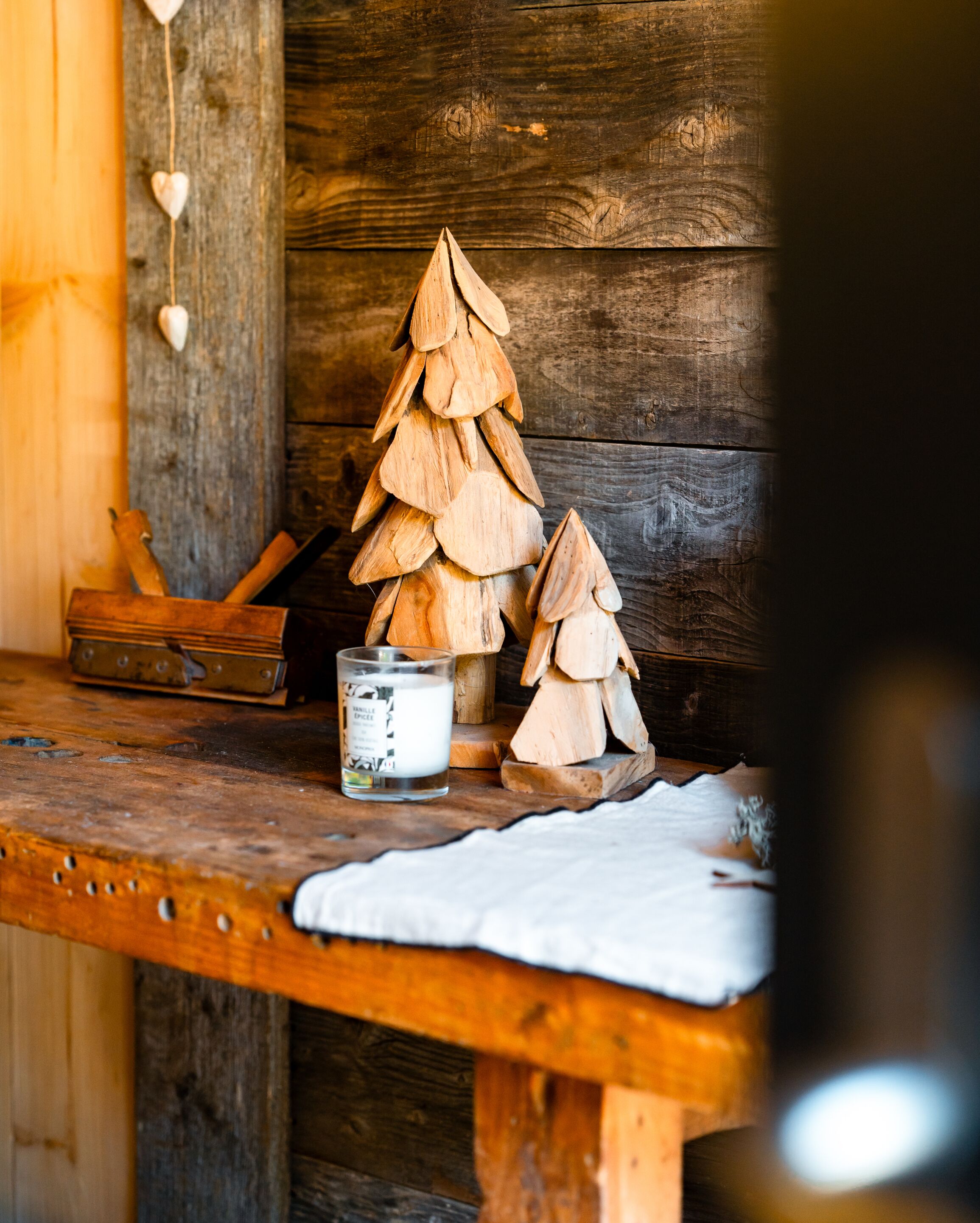 Een houten tafel in rustieke stijl met een kleine houten kerstboom, een kaars en een houten doos.