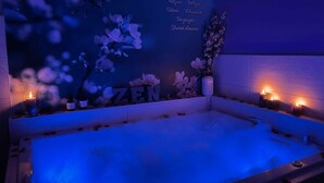 Un espace spa à l’ambiance zen, doté d’une grande baignoire, de décorations florales et de bougies.