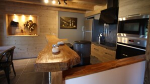 Une cuisine moderne avec des meubles en bois, un réfrigérateur en acier inoxydable, un four et une table à manger en bois ornée de quelques pierres.