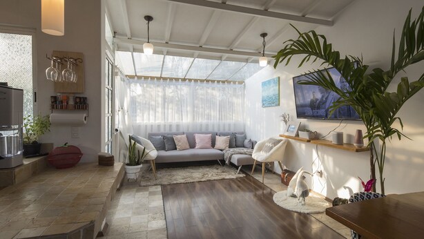A spacious living room with a large window, a sofa, a coffee table, and a television.