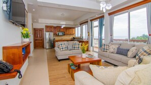 A spacious living area with a sofa, coffee table, and a kitchen in the background.