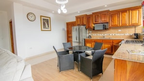 A modern kitchen with wooden cabinets, a stainless steel refrigerator, and a round dining table with wicker chairs.