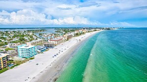 A coastal hotel with a beachfront view, multiple stories, and a sandy beach.