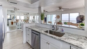 A spacious kitchen with a granite countertop, stainless steel sink, and white cabinetry.