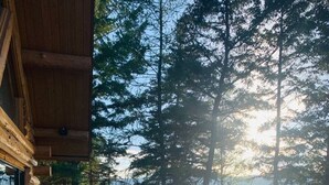 A wooden deck with a railing overlooking a lake surrounded by trees. - Christy's Cottage, Waterfront w/slide & Ice Shanty (Kalispell)