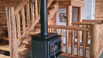 A wooden staircase with a black wood-burning stove in the center.