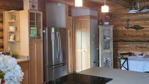 A kitchen with wooden cabinets, a stainless steel refrigerator, a built-in oven, and pendant lights. - Christy's Cottage, Waterfront w/slide & Ice Shanty (Kalispell)
