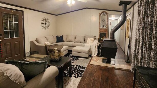 A living room with a ceiling fan, a fireplace, a sofa, and a coffee table. - Animal Village/W/Mountain Views (Kalispell)