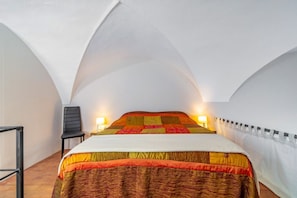 Une chambre à coucher avec un lit, une chaise et une table de chevet avec une lampe.