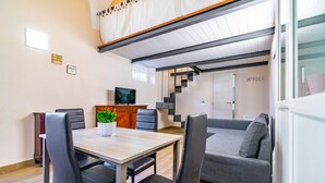Una stanza in stile loft con zona pranzo, divano, scala e televisione.