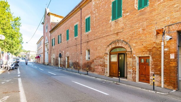 Un edificio in mattoni con un'ampia porta ad arco e persiane verdi.