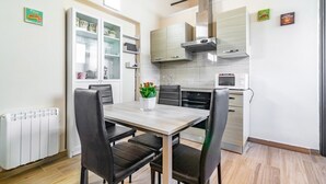 Una cucina moderna con un tavolo da pranzo, sedie, armadietti, un forno a microonde e un forno integrato.