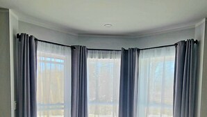 A room with a large window, a dark-colored sofa, and a white bed. - Contemporary 3 bedroom apartment on the first floor overlooking the Salmon River (Pulaski)