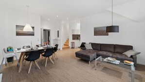 A modern living room with a sofa, coffee table, and dining area with chairs and a table. - Gorgeous home in Loxstedt with WiFi (Loxstedt)