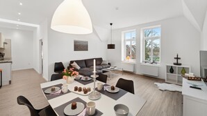 A modern living room with a dining area, featuring a large pendant light, a sofa, a coffee table, and a view of the outside through large windows. - Gorgeous home in Loxstedt with WiFi (Loxstedt)