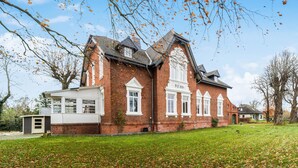 A large, red brick building with white trim and a gabled roof, featuring a small attached structure with a white exterior. - Gorgeous home in Loxstedt with WiFi (Loxstedt)