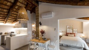A compact, modern kitchen with a dining area, a small island, and a cozy bedroom with a bed and nightstand.