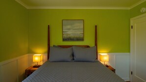 A bed with a wooden headboard, two bedside lamps, and a painting on the wall. - Work away ready, dog friendly. Downtown Tillamook - Modern Vintage (Tillamook)