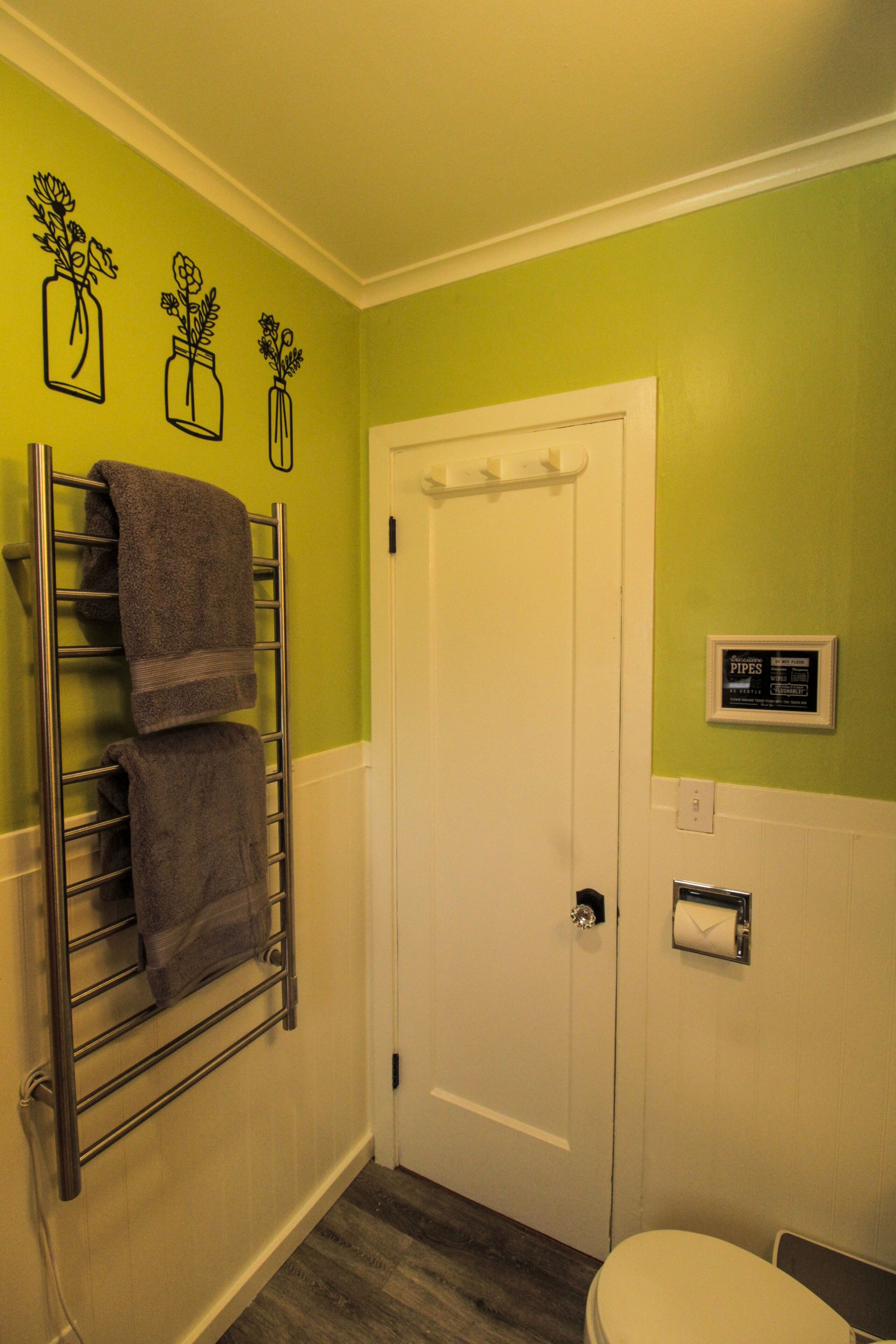 A bathroom with a towel rack, a toilet, and a door with a sign above it.