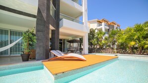 A modern hotel with a pool area, including a wooden deck and lounge chairs. - Marea Azul Beach Resort  (Playa del Carmen)