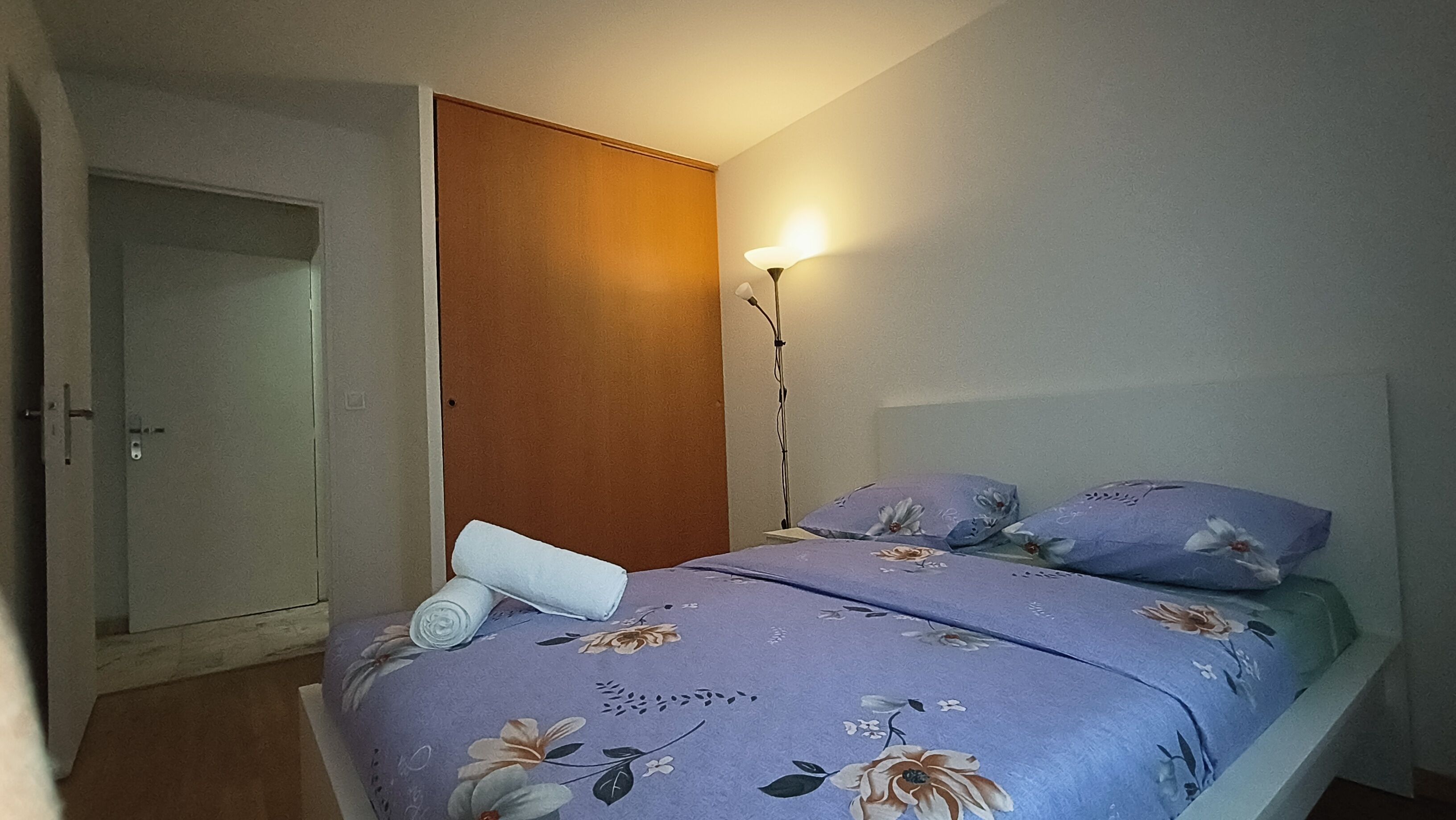 Ein Schlafzimmer mit einem Bett, einem Nachttisch, einer Lampe und einem Kleiderschrank.