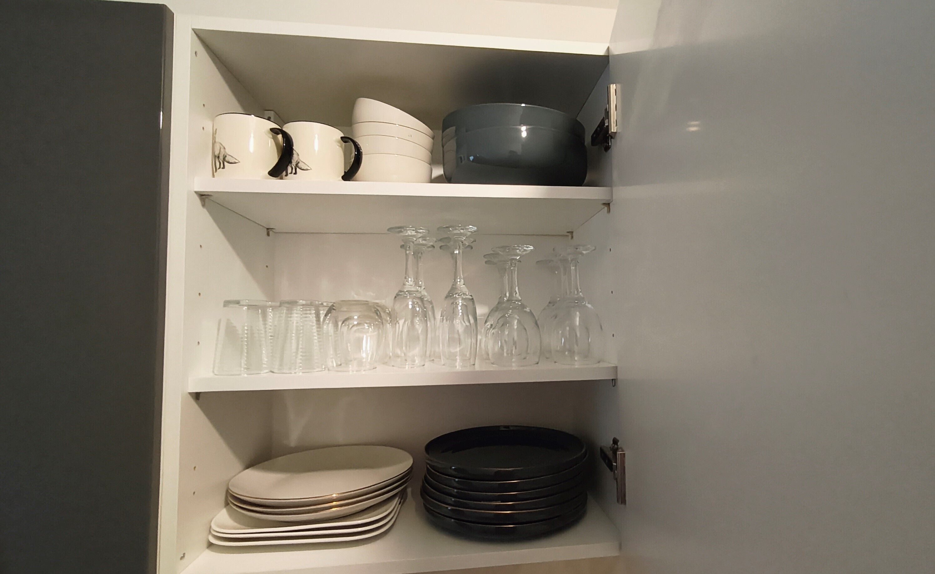 A kitchen cabinet with shelves holding various kitchenware.