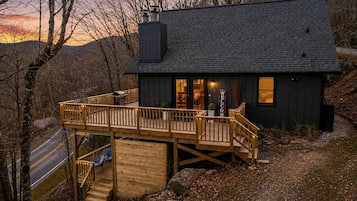 A cabin with a deck, a chimney, and a 'WELCOME' sign.