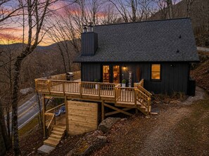 Une cabane avec une terrasse, une cheminée et une pancarte indiquant « BIENVENUE ».