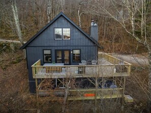 A two-story cabin with a balcony, surrounded by trees.