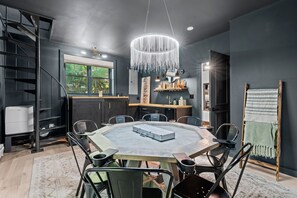 A modern dining area with a round table, chairs, and a chandelier.