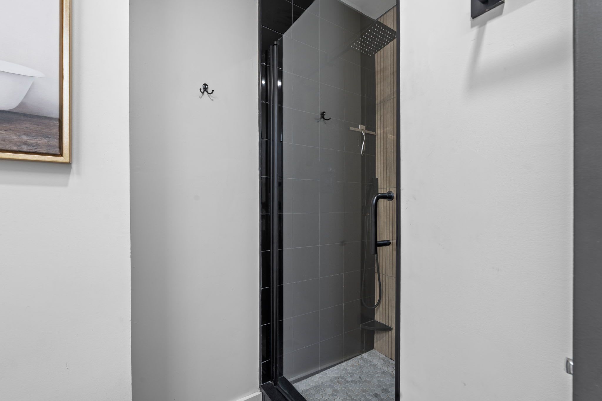 Une salle de bain moderne avec une douche à parois de verre, un mur recouvert de panneaux en bois et un sol carrelé.