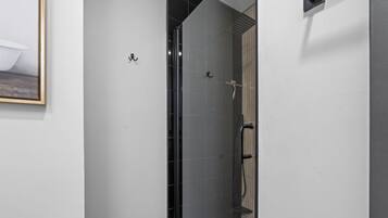 Une salle de bain moderne avec une douche à parois de verre, un mur recouvert de panneaux en bois et un sol carrelé.