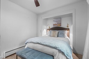 Une chambre à coucher avec un lit, des lampes de chevet, un banc et un tableau au mur.