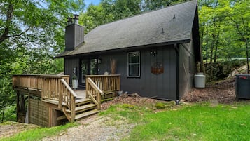 A cabin with a wooden deck, a chimney, and a well-maintained garden.