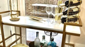 Carrito metálico de varios niveles con botellas de vino, copas y una discreta campana de arena.