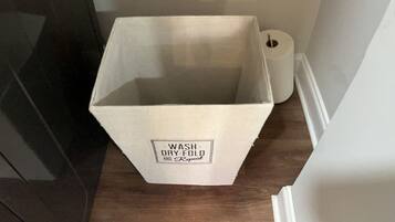 A kitchen with shelves holding jars, a plant, and a white box labeled "WASH-DRY-FOLD."