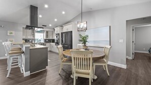 Una cocina moderna con una isla central, armarios blancos y un comedor con una mesa redonda y sillas.