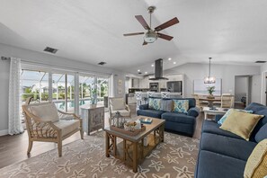 A spacious living area with a pool view, a ceiling fan, and a dining area. - Serenity on the Cape - Heated Pool - Jacuzzi - Canal Views (Cape Coral)